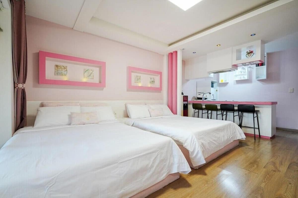 A bedroom with two beds, a kitchenette, and a dining area.