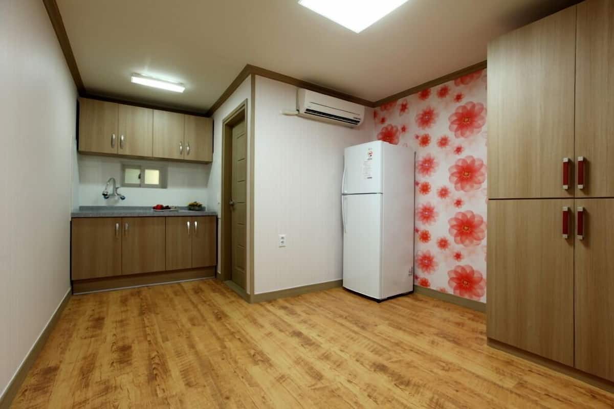A compact kitchen with wooden cabinets, a white refrigerator, and a floral-patterned wall.