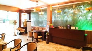 A reception area with a counter, chairs, and a decorative plant. - Hotel Bright Heritage (Kochi)