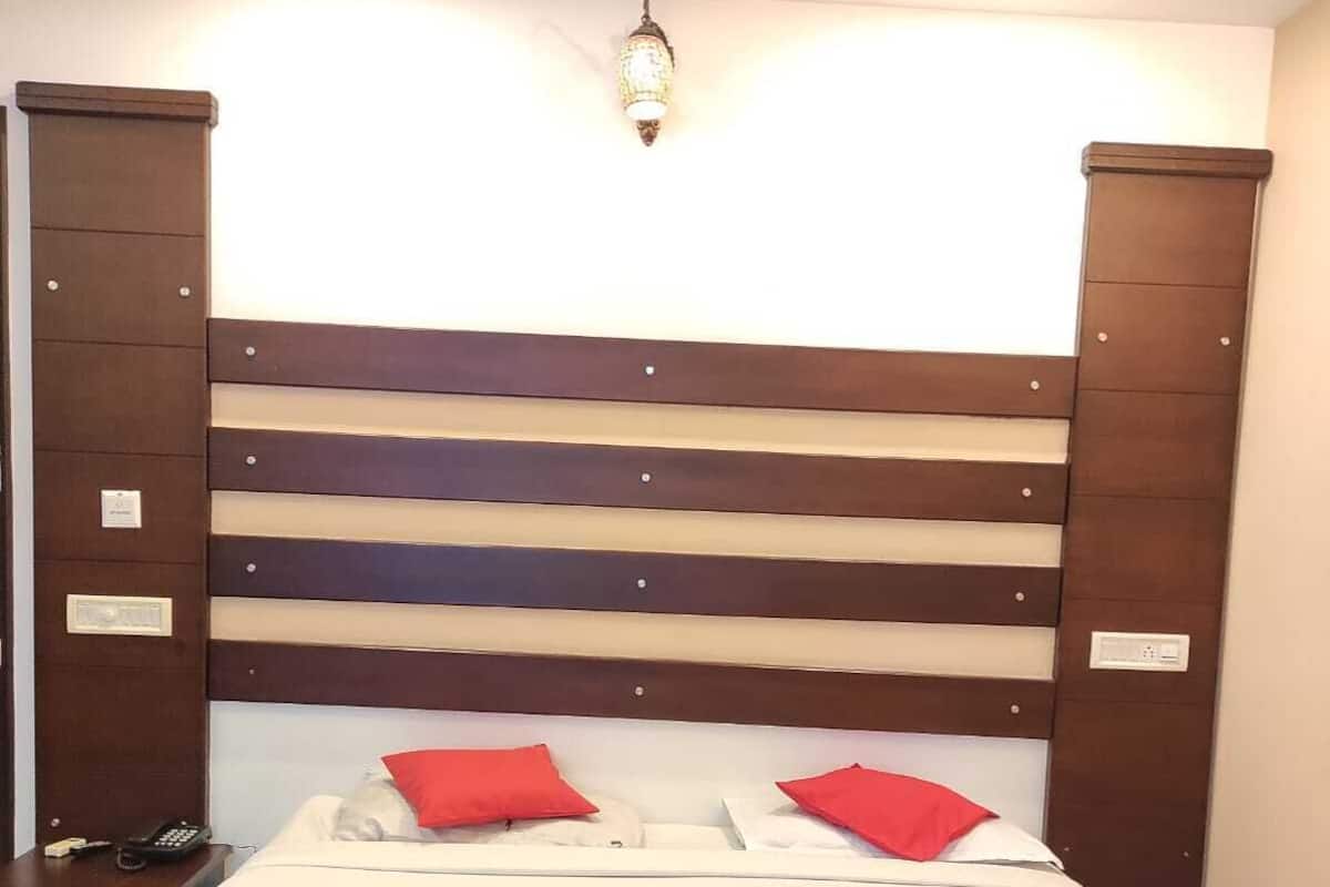 A hotel room with a bed, two nightstands, a telephone, and a wall-mounted light fixture.