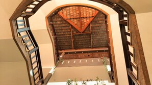 A view of a wooden staircase with a vaulted ceiling and a wooden railing. - Hotel Bright Heritage (Kochi)