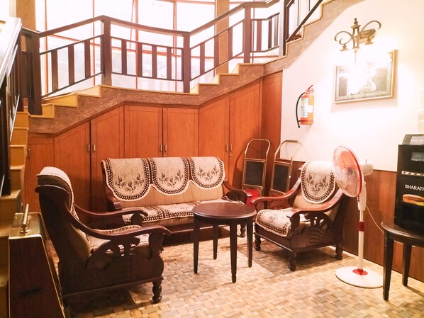 A traditional room with a wooden staircase, a sofa set, a table, and a fan.