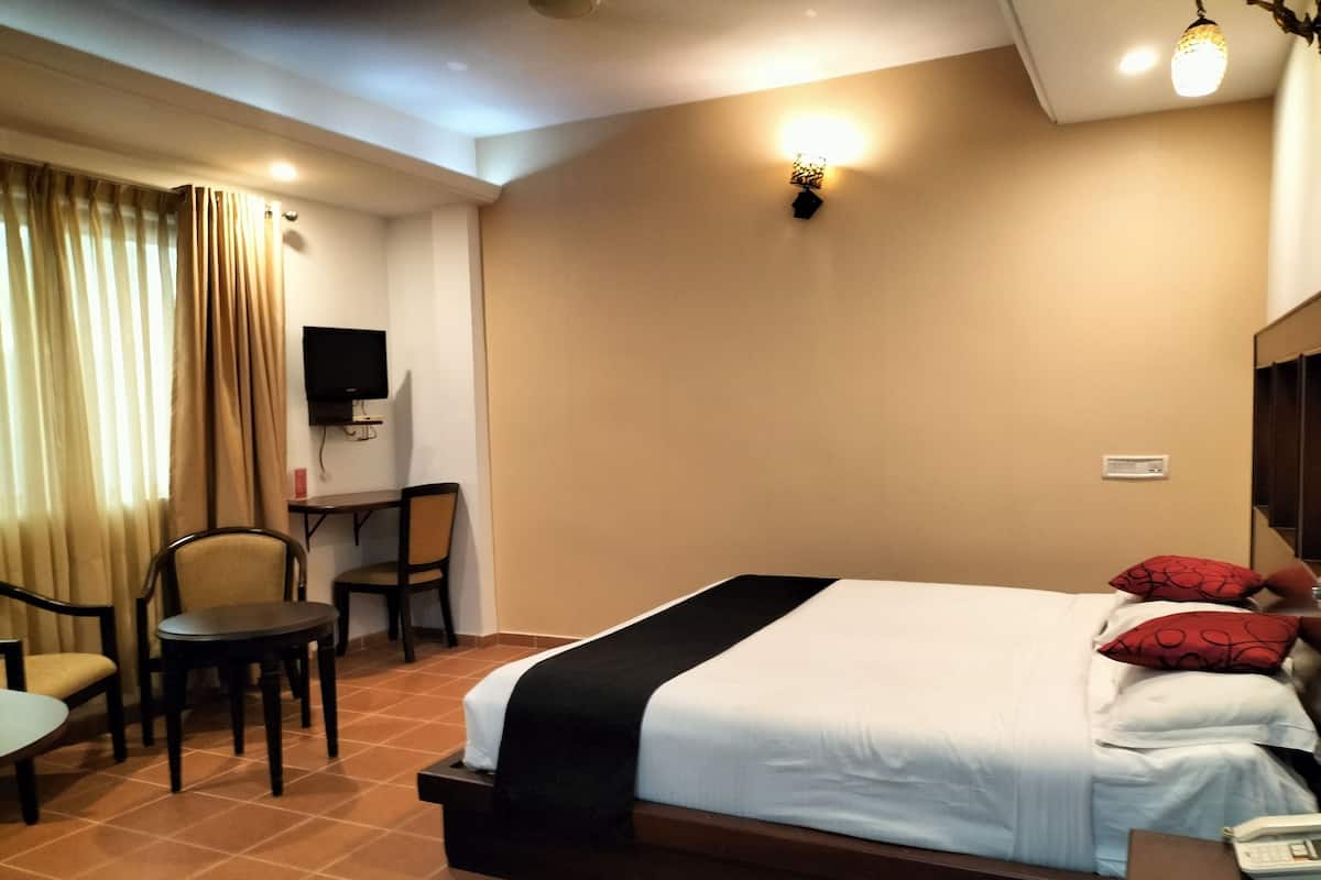 A hotel room with a bed, a desk, a chair, and a television.