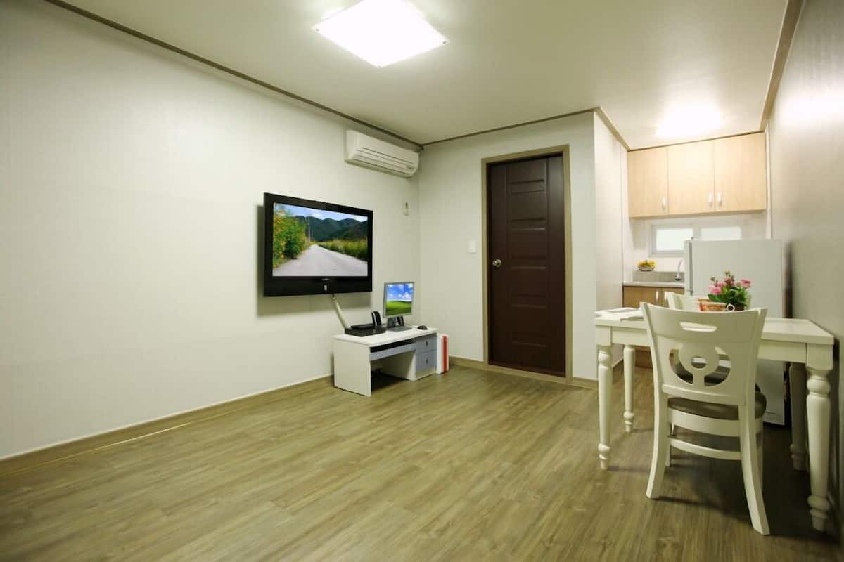 A small, clean room with a desk, chair, and a television mounted on the wall.