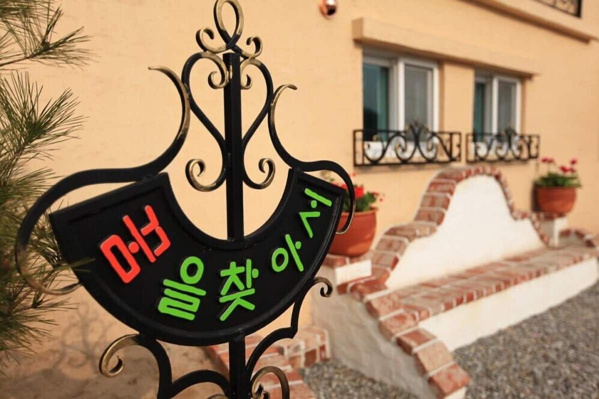 A black metal sign with Korean characters and a digital clock displaying 0:13.