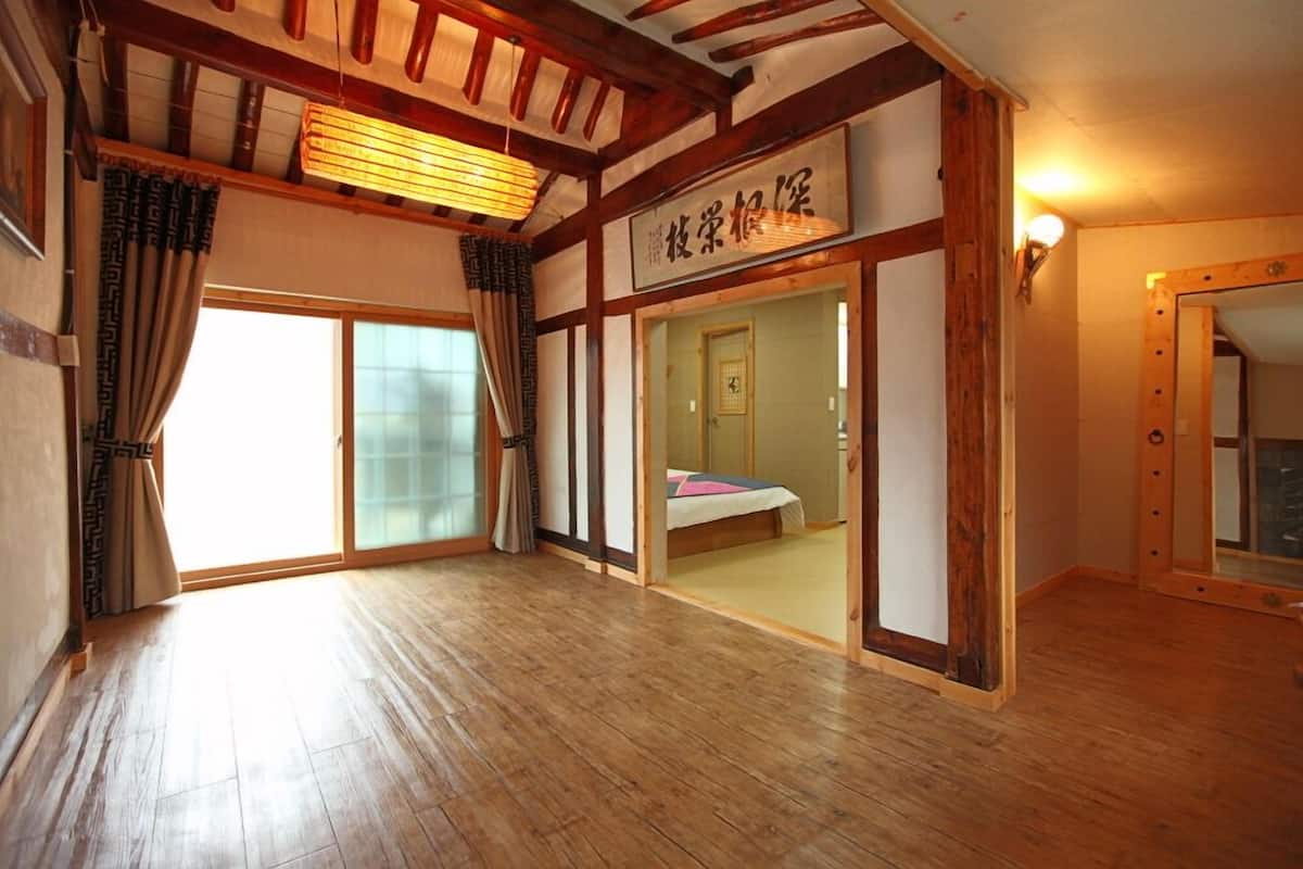 A traditional Japanese room with tatami flooring, sliding doors, and a bed with a pink and white bedding.