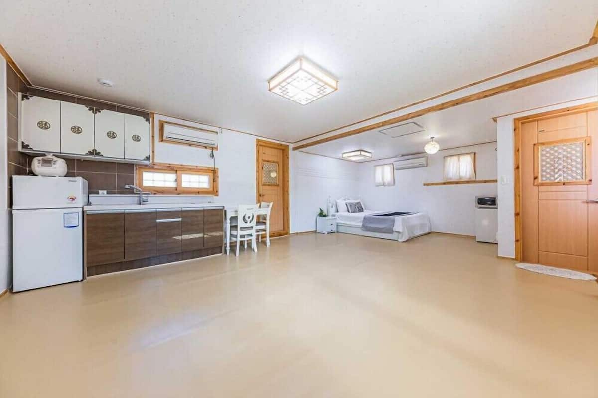 A spacious kitchen with a dining area, a sofa, and a wooden door.
