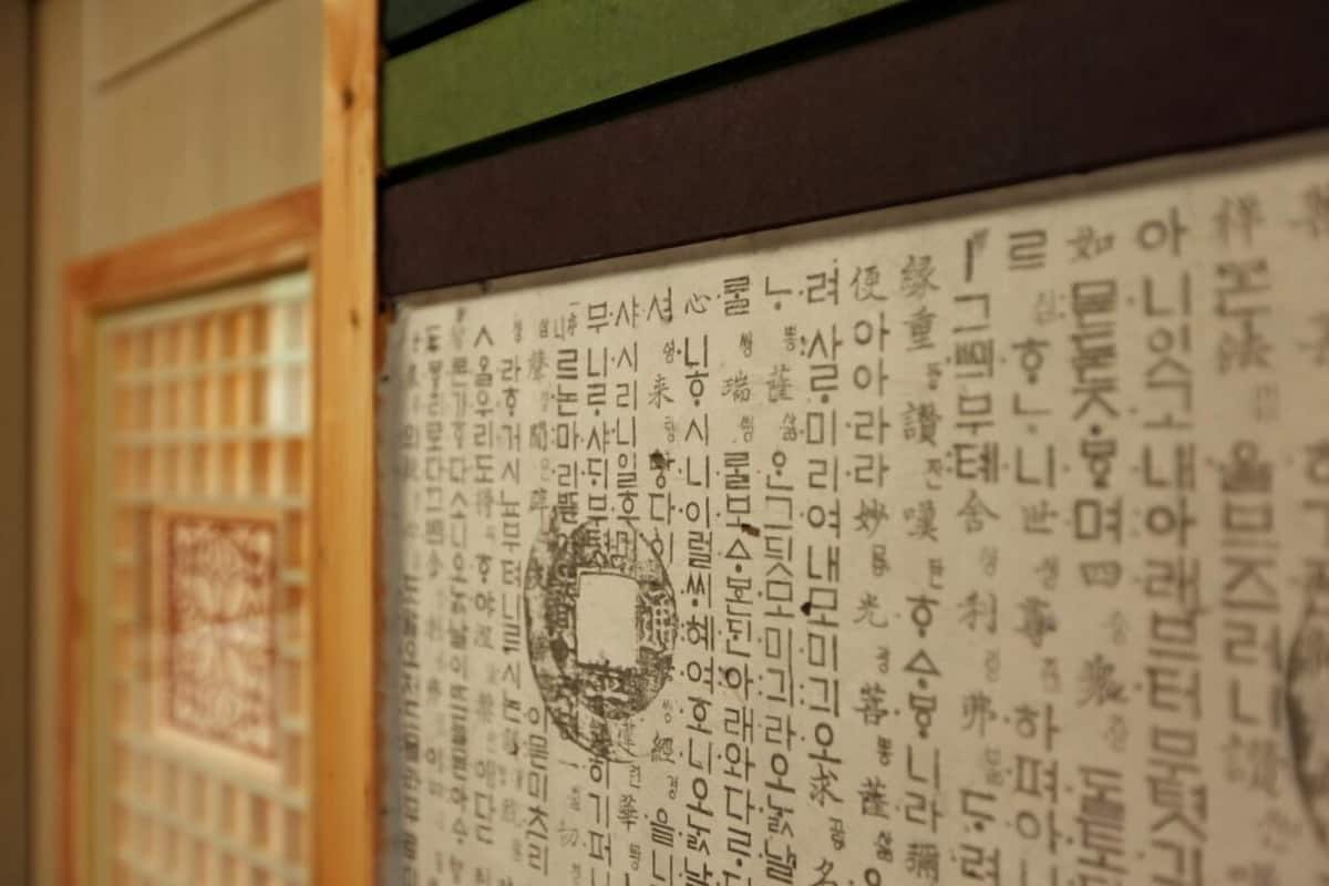 A wall with Korean text, a window with a grid pattern, and a wooden frame.