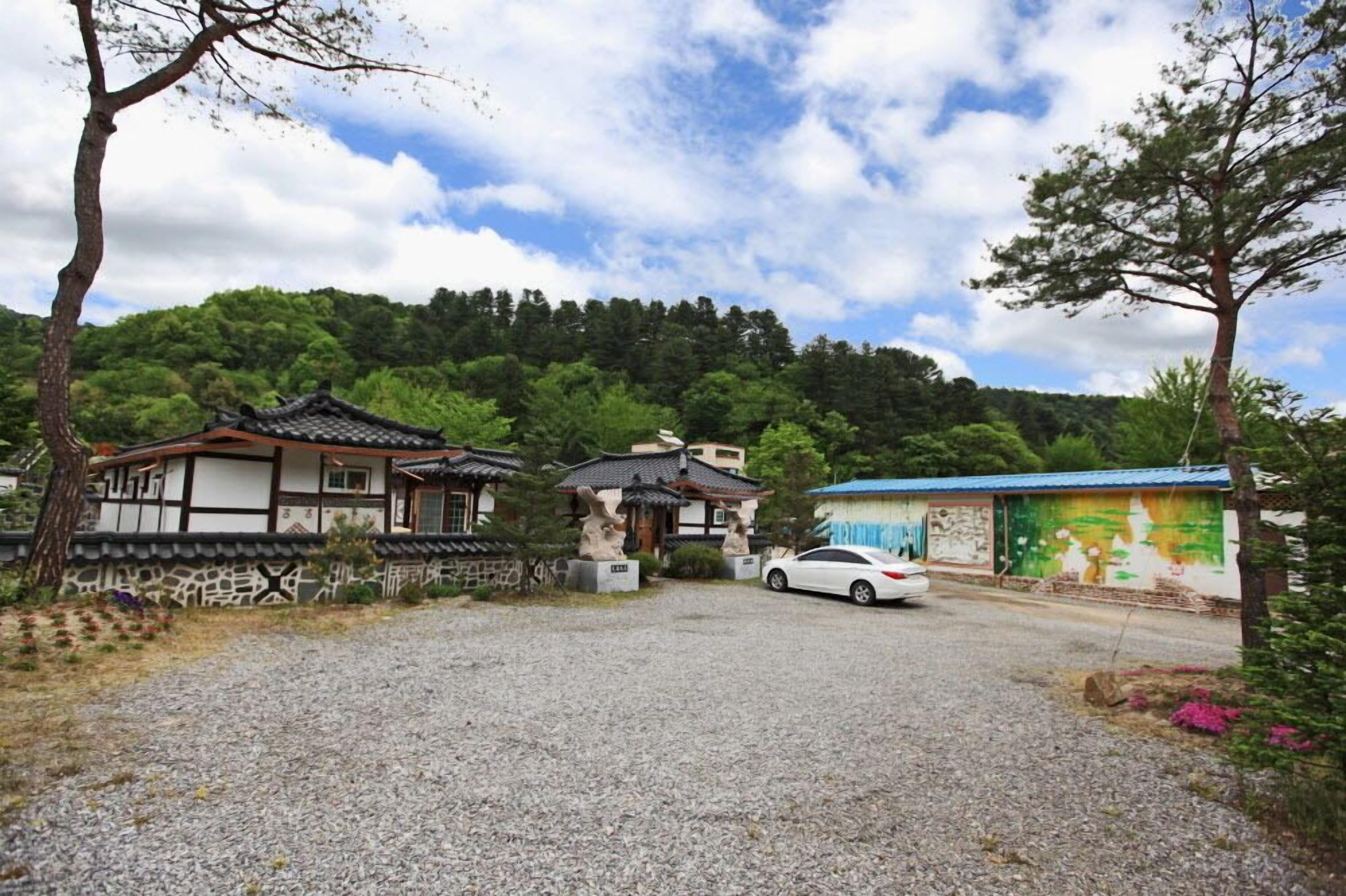 A traditional Korean-style building with a tiled roof and a small garden area.