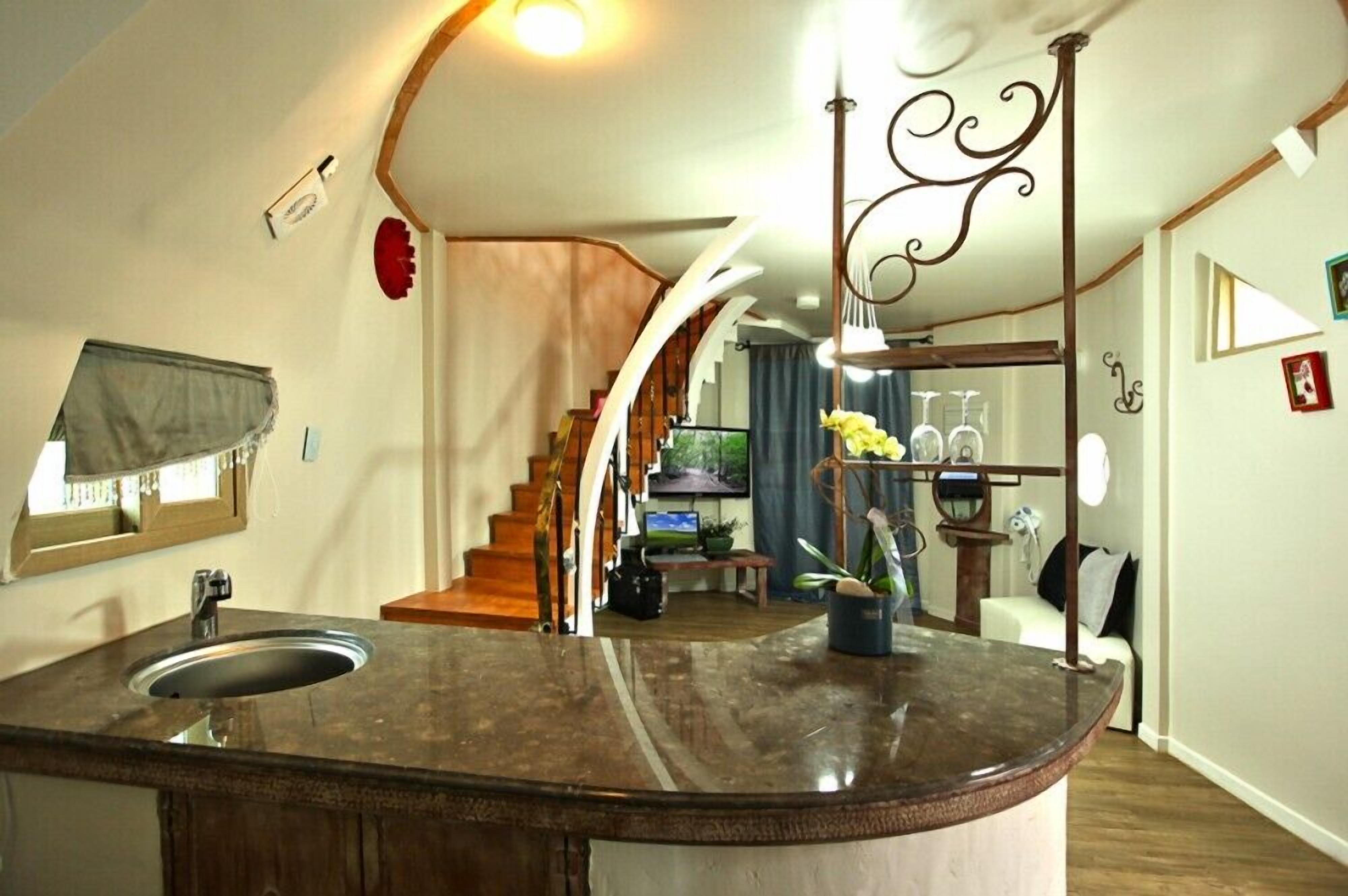 A kitchen with a curved island, a built-in sink, and a staircase leading to another level.