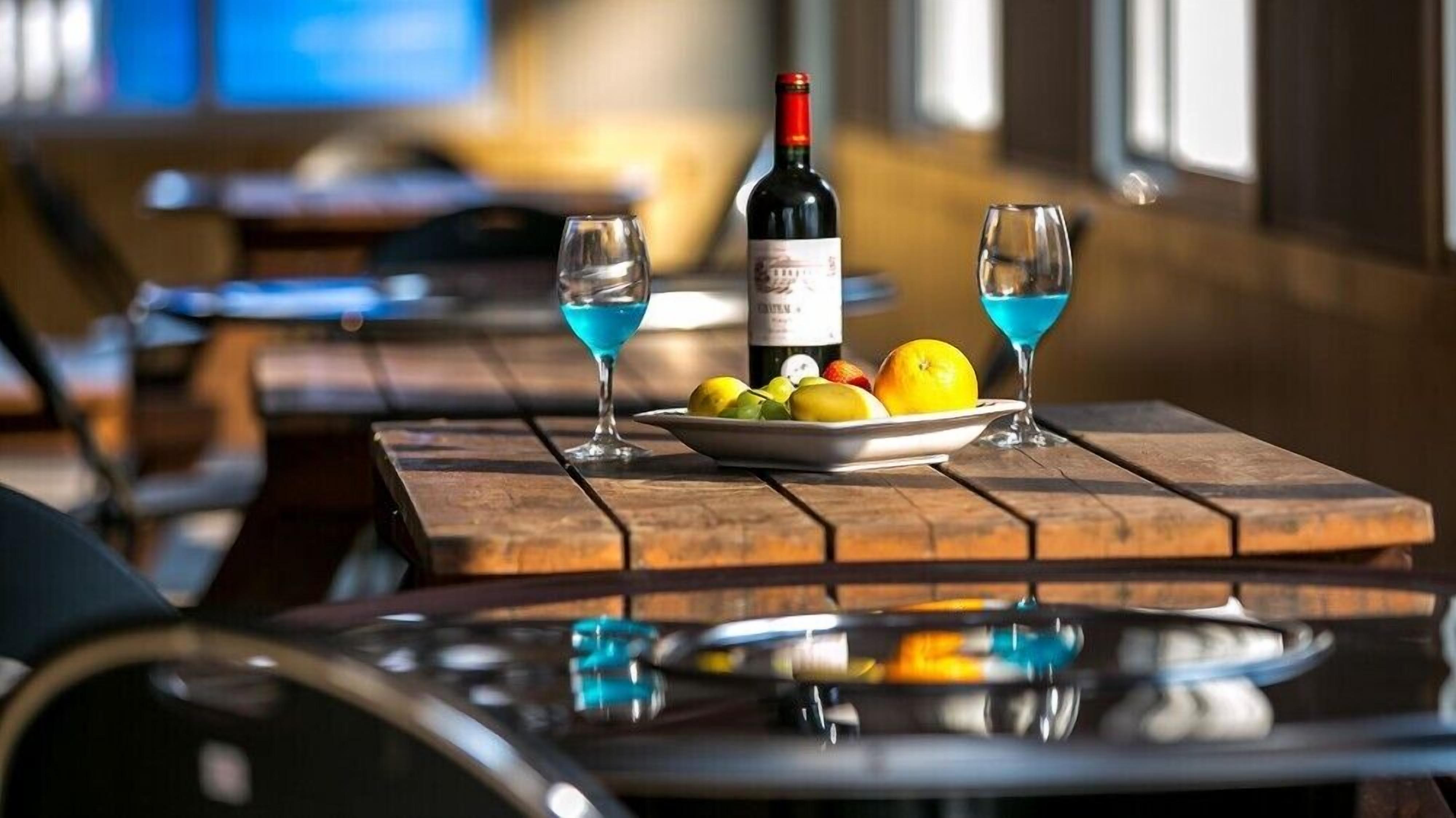 A table with a bottle of wine, two glasses, and a plate of fruit.