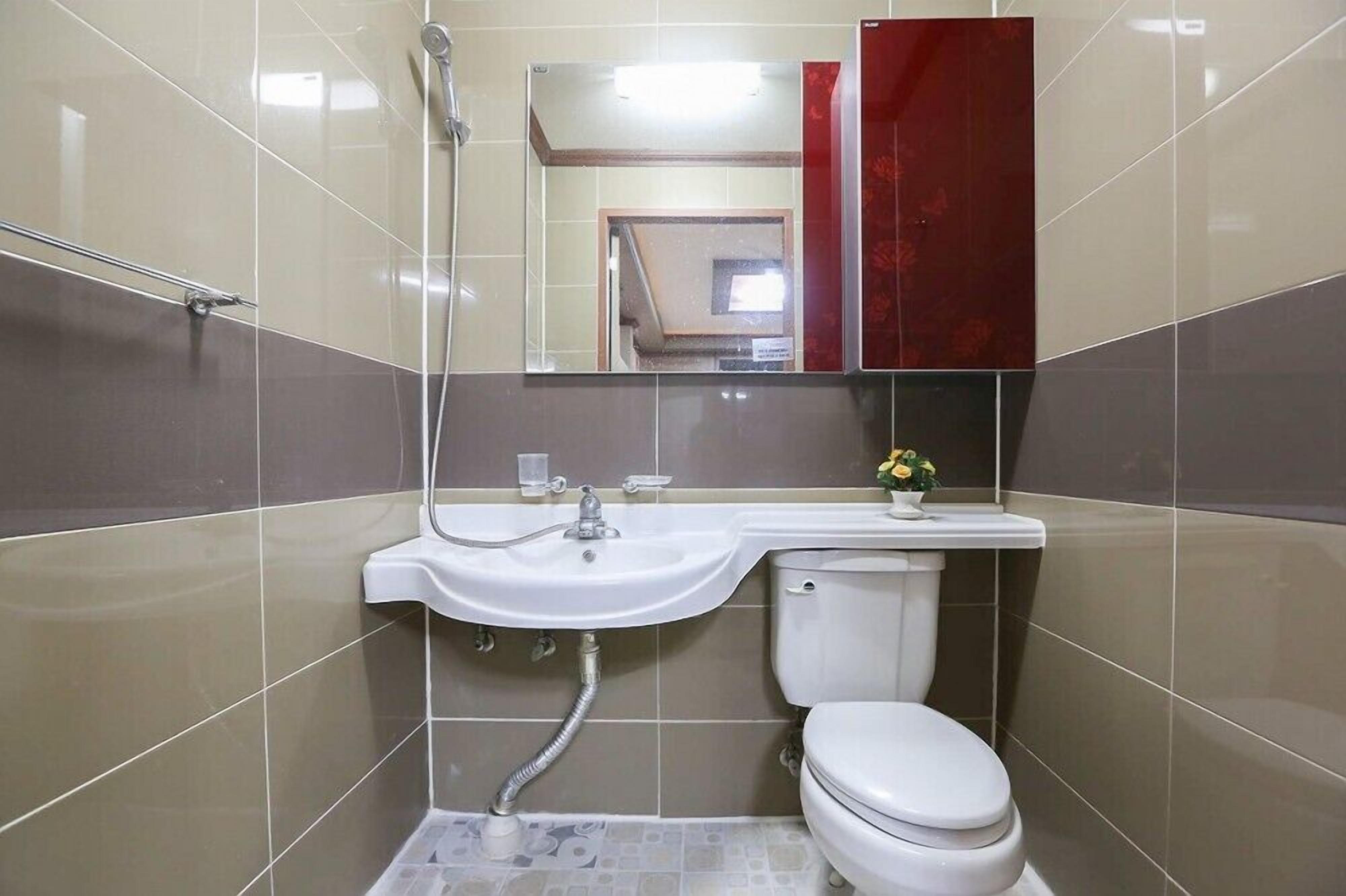 A bathroom with a white sink, mirror, and toilet.