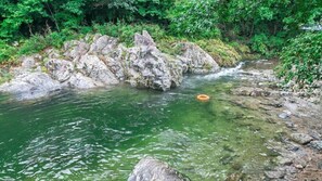Un río cristalino con rocas y un aro flotando, rodeado de vegetación exuberante.