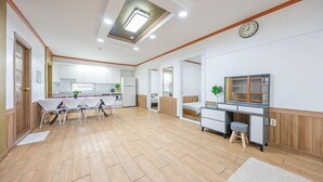A spacious living area with a kitchen, dining table, and a TV. - Eco Pia Pension (Gapyeong)