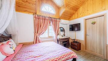 Un dormitorio con cama, tocador con espejo, televisor en la pared y puerta de madera.