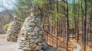 A stone structure in a forested area with a metal fence and a stone pathway.