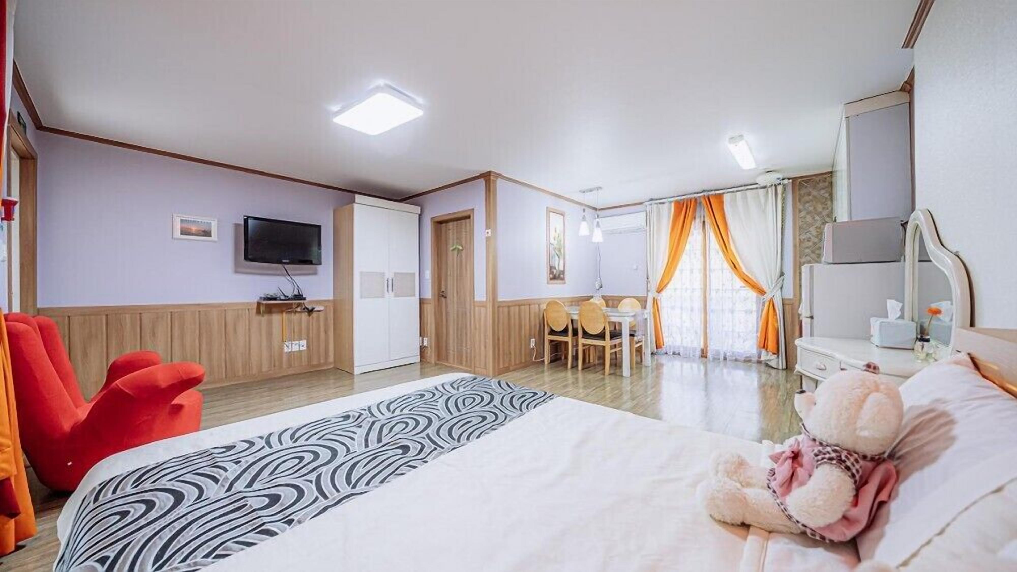 Hotellihuone, jossa on sänky, televisio, työpöytä ja tuoli.