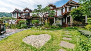 A two-story house with a landscaped garden featuring a heart-shaped gravel area and stepping stones.