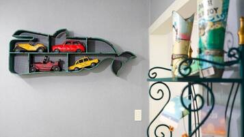 Un estante montado en la pared con coches de juguete y una estructura decorativa con forma de pez.