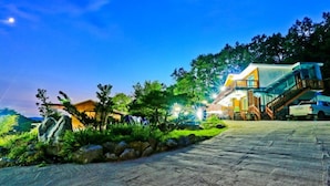 A modern hotel with a stone-paved entrance, a well-maintained garden, and a two-story building with a balcony. - Sambatgol Pension (Pocheon)