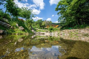 A serene river with clear water reflecting the surrounding greenery and a clear sky. - Sambatgol Pension (Pocheon)