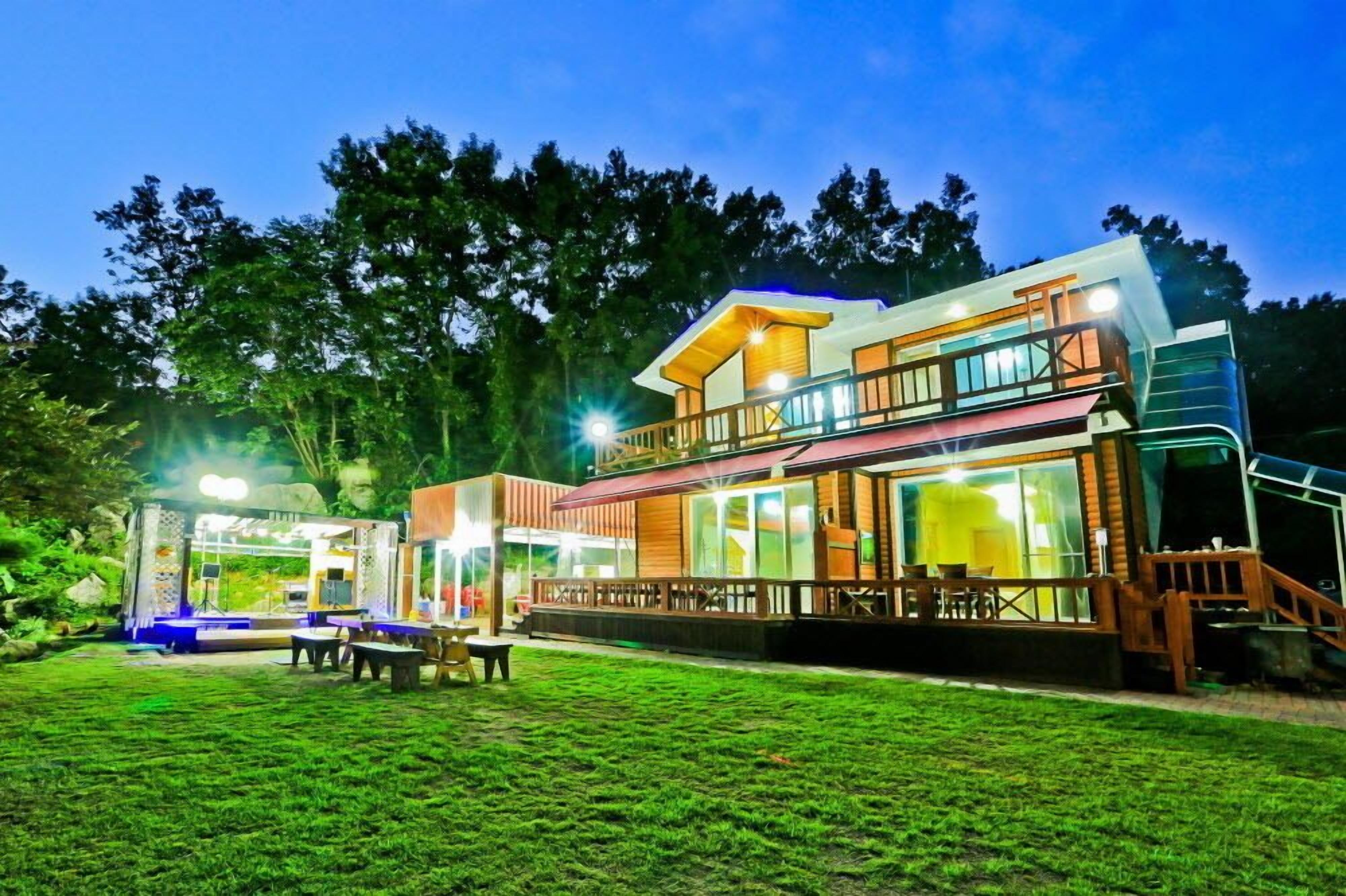 A modern two-story building with a glass facade, outdoor seating area, and a well-lit entrance.