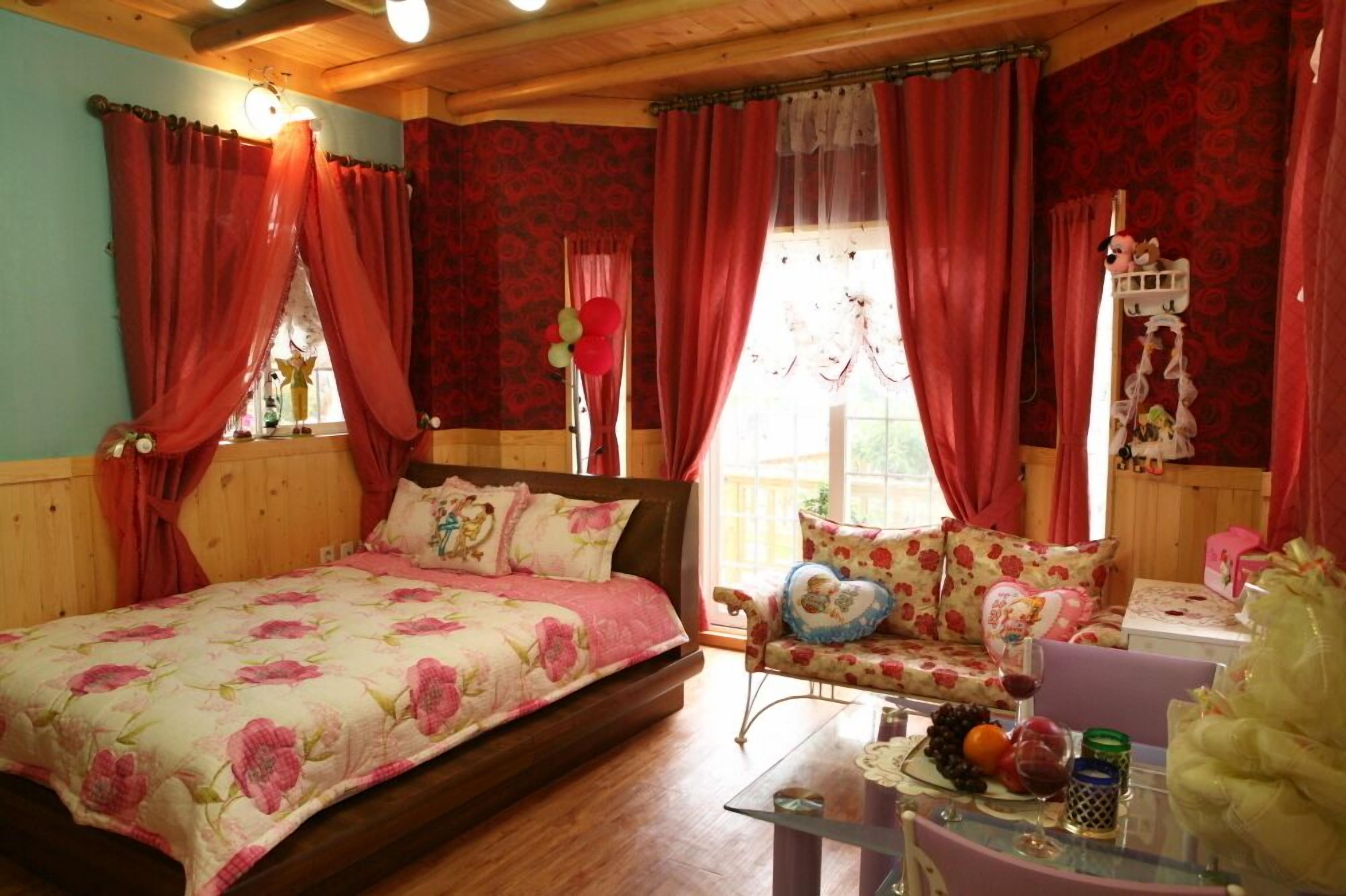 A cozy room with a bed, a sofa, and a table with fruit and a glass of wine.