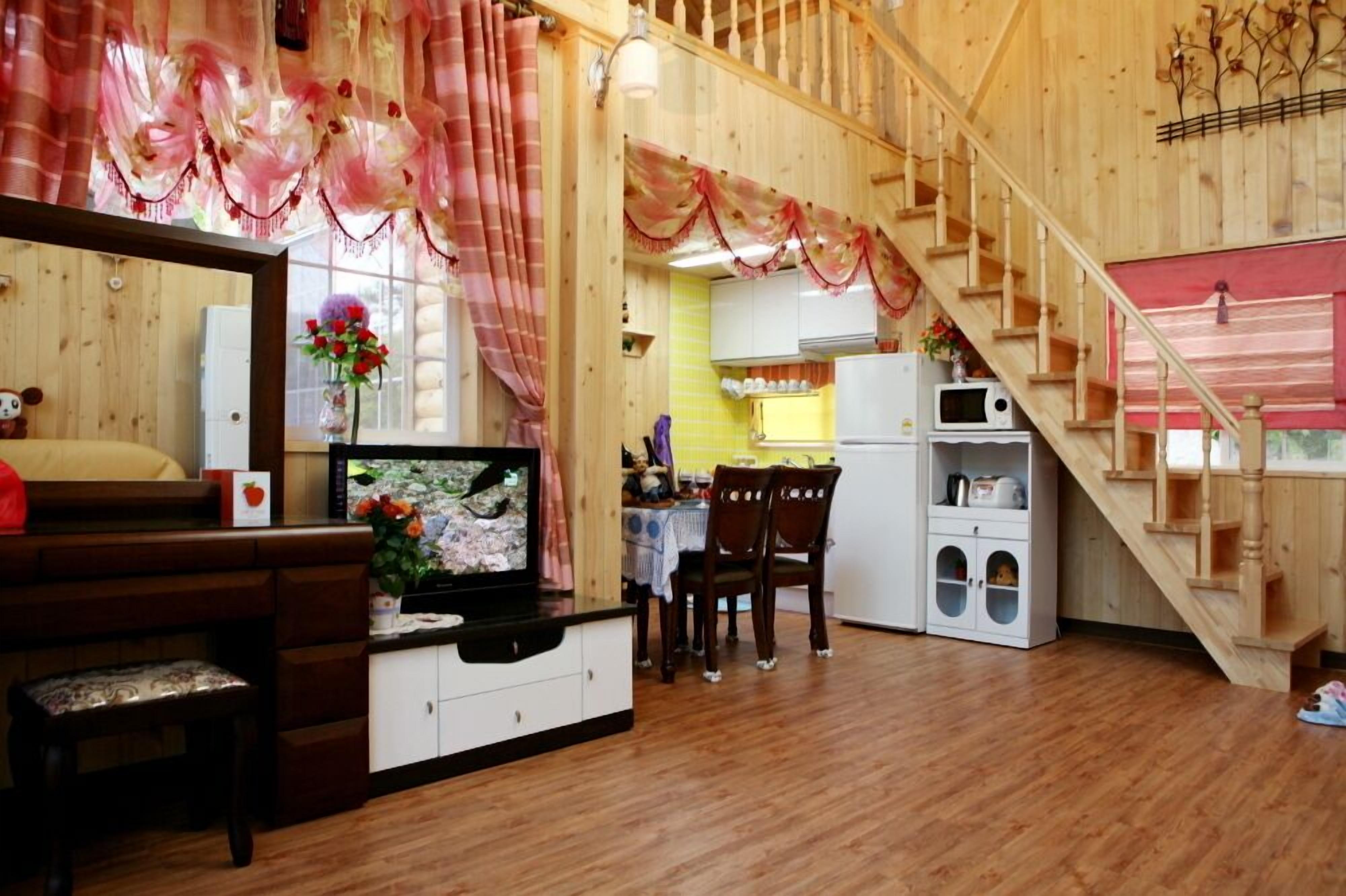 A cozy cabin interior with a wooden staircase, a dining area, and a kitchen.