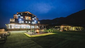 A large, modern hotel with multiple floors, a covered outdoor area with seating, and a well-lit lawn. - Milky Way Pension (Gapyeong)