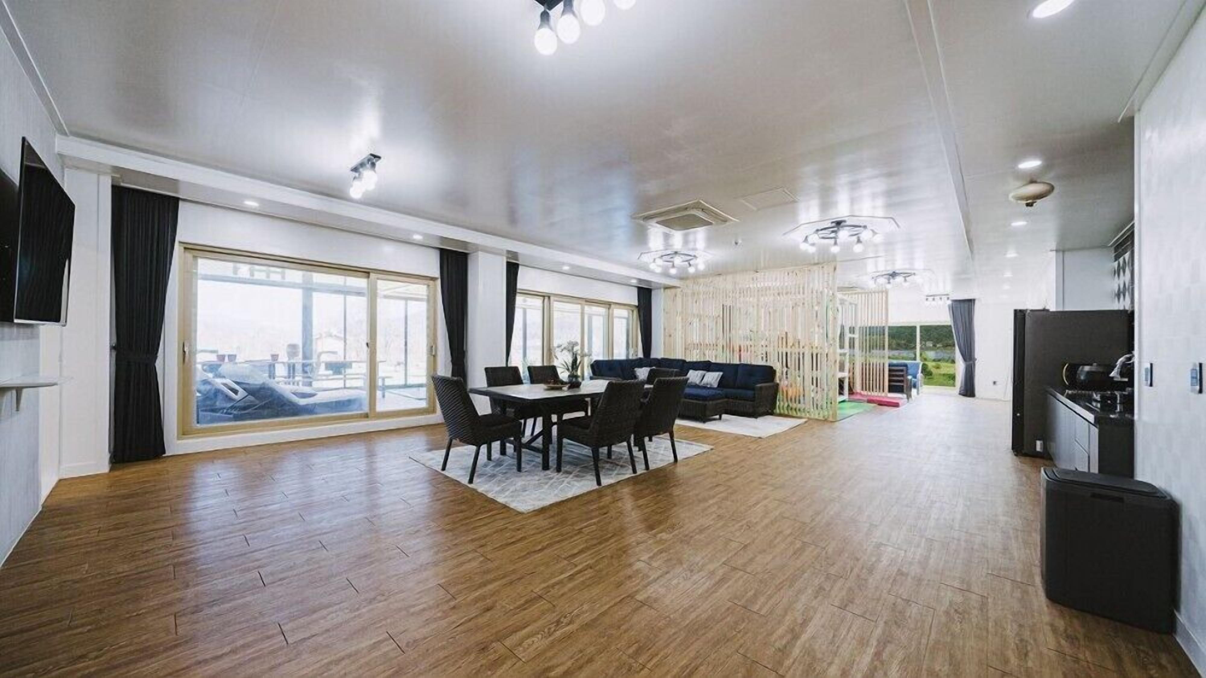 A spacious living area with a dining table, sofa, and large windows offering a view.