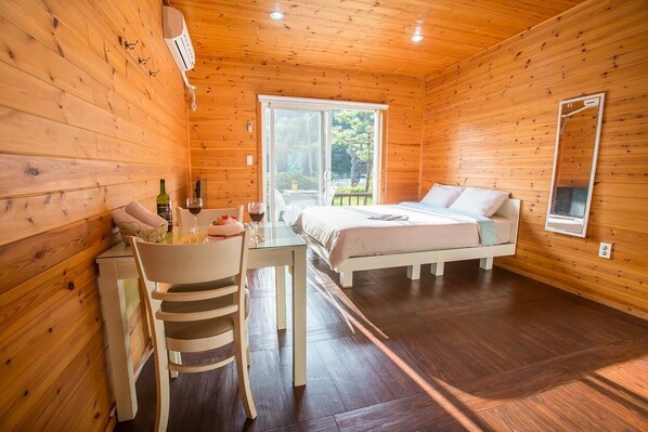 A wooden cabin with a bed, a table with chairs, and a window.