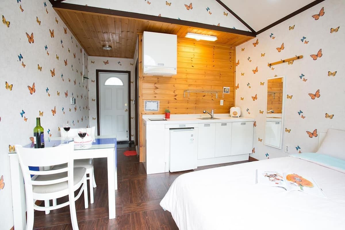 A compact room with a kitchenette, a dining area, and a bed.