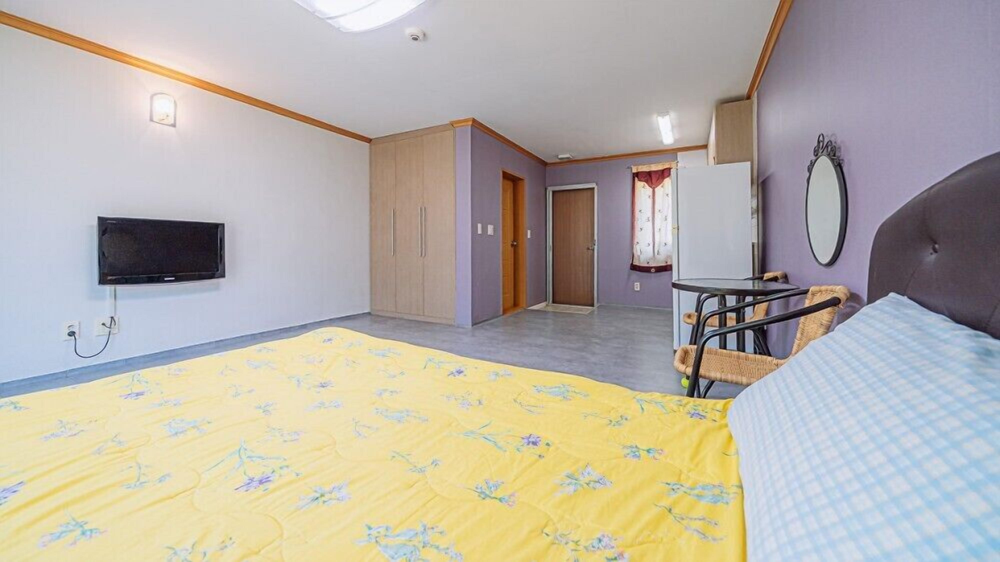 Une chambre avec un lit, une télévision, une petite table et une chaise.