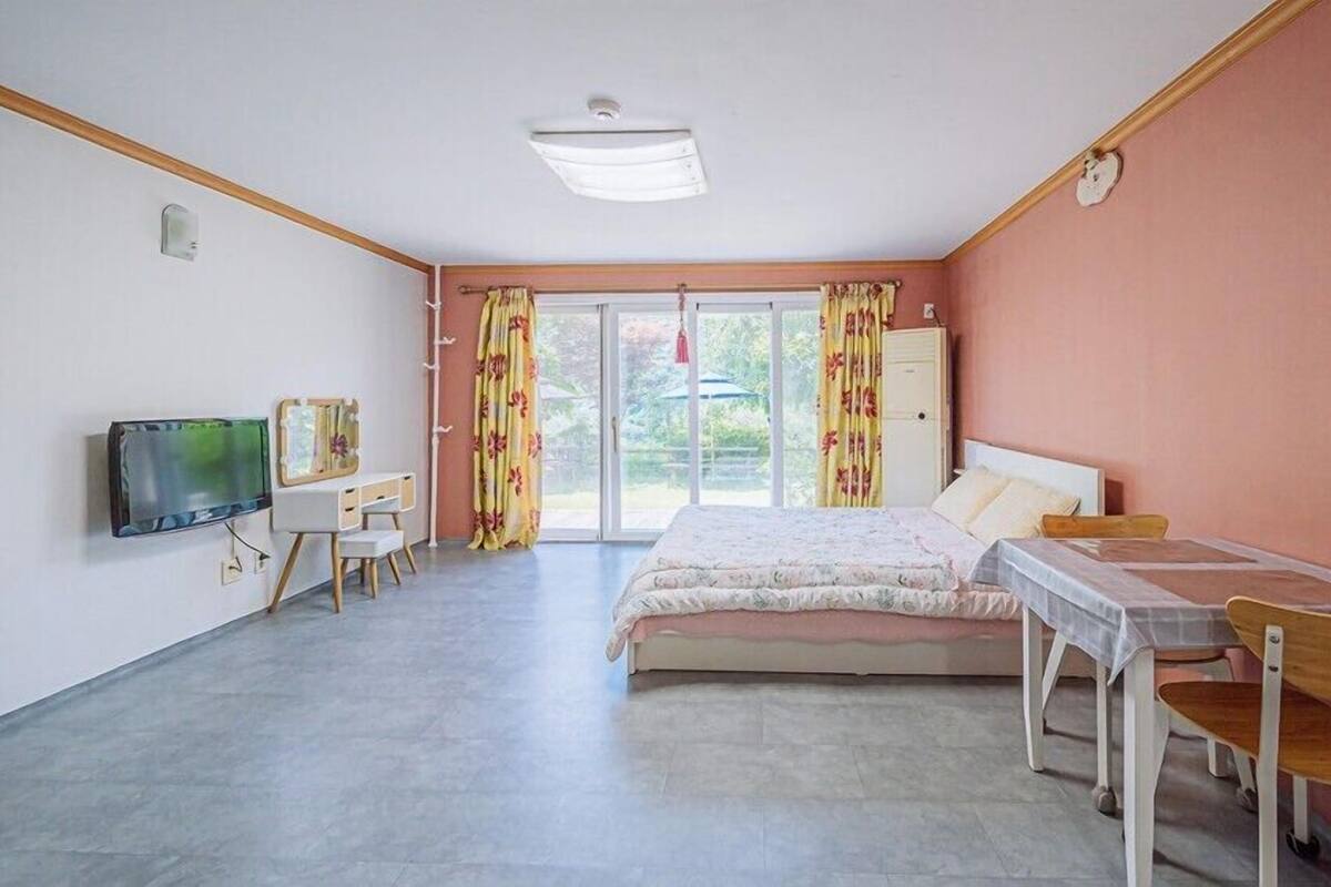 A bedroom with a bed, a desk, a chair, a television, and a wardrobe.