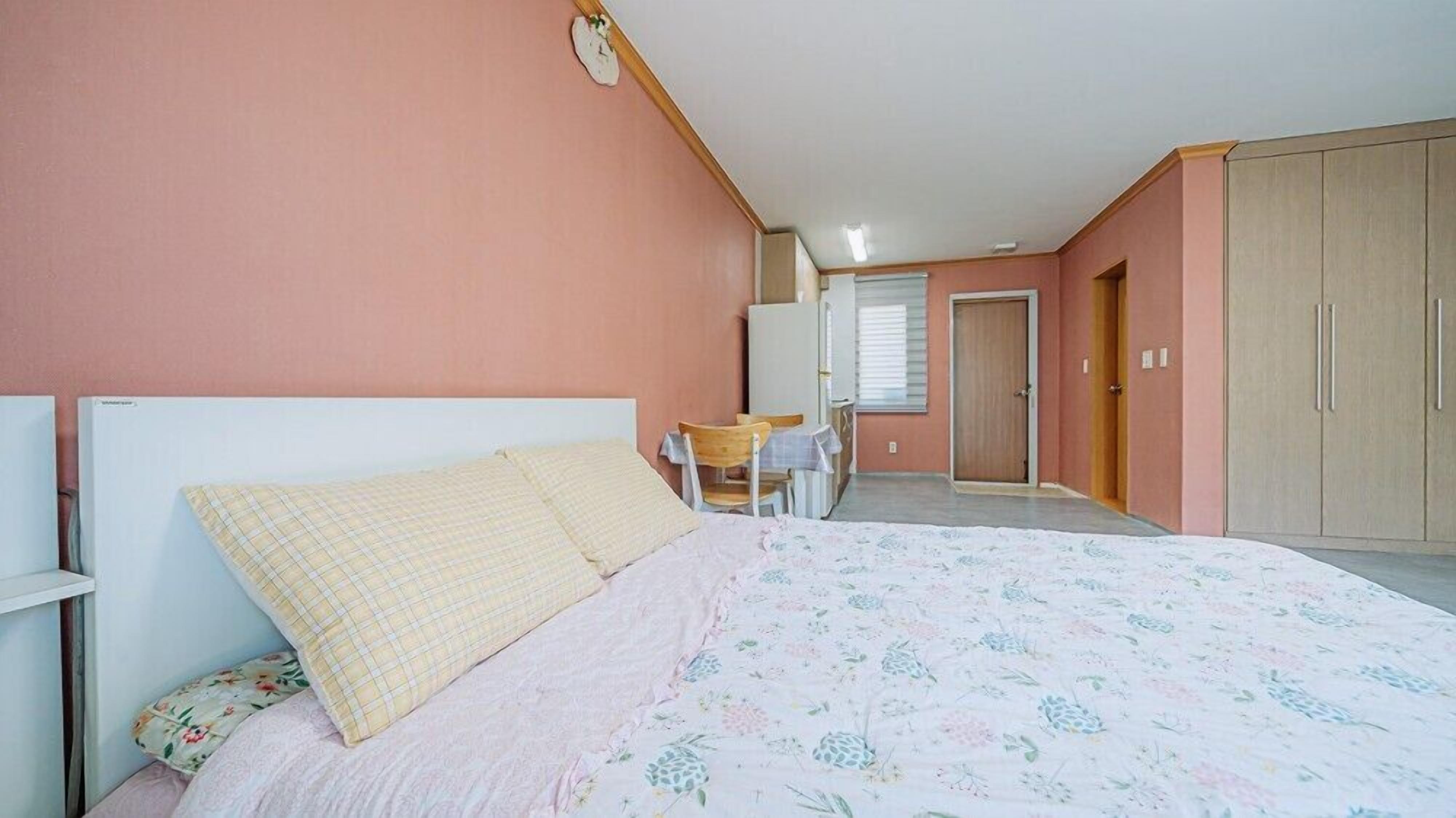 Ein Schlafzimmer mit Bett, Stuhl, Tisch und Kleiderschrank.