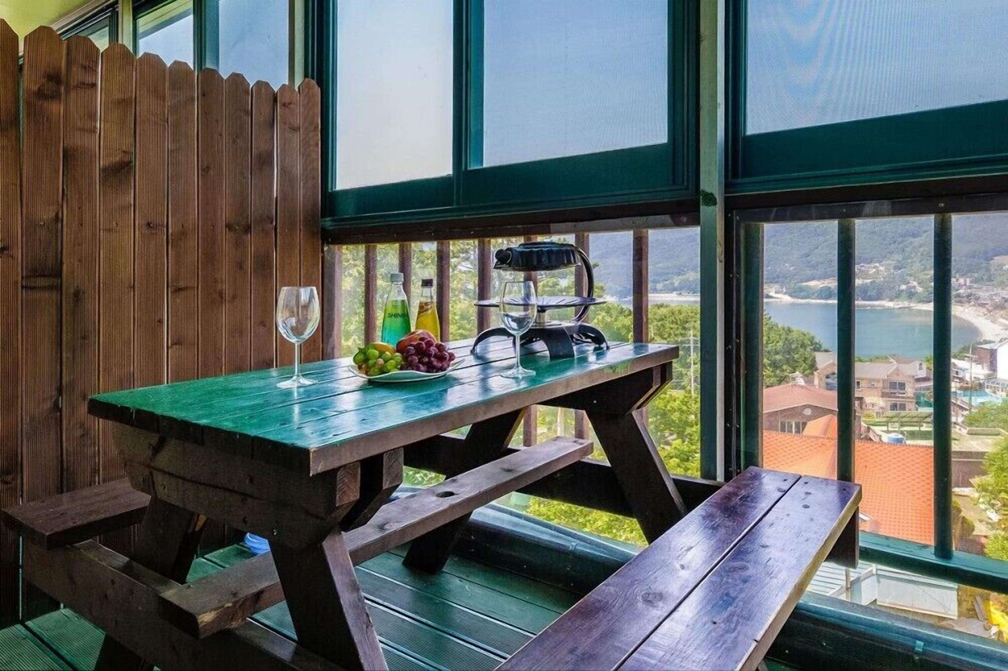 Um deck de madeira com uma mesa para piquenique, uma taça de vinho e uma saladeira.