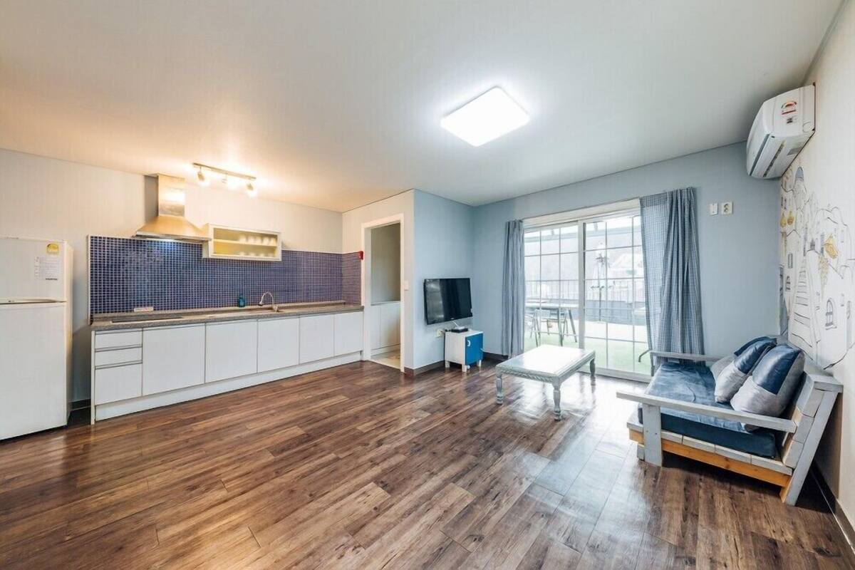 A spacious living area with a kitchen, a sofa, and a TV.