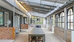 Una habitación amplia con una mesa grande, ventanas amplias y una pared de ladrillo decorativa.