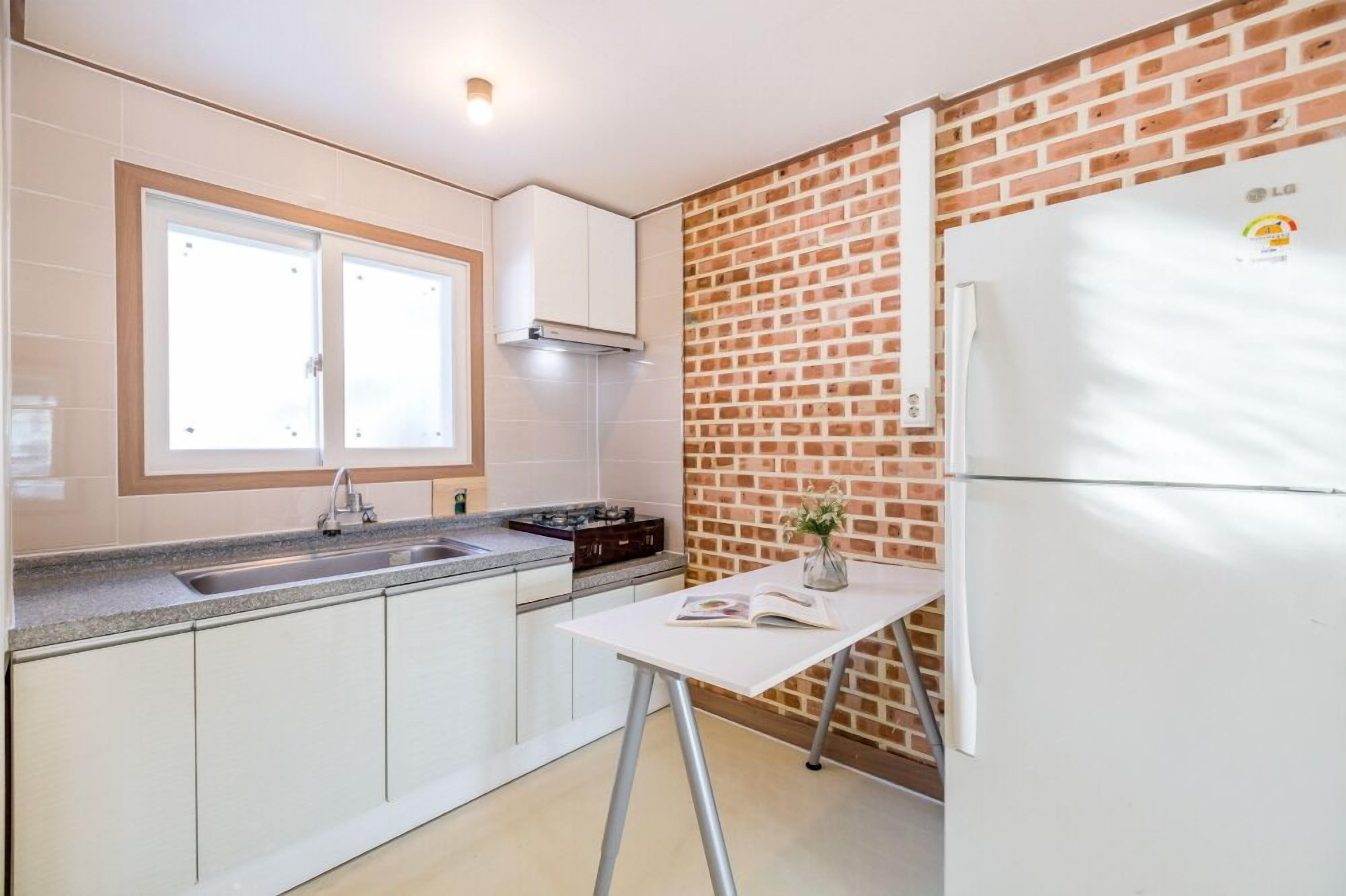 Una cocina con gabinetes blancos, un lavamanos doble, una estufa a gas y un refrigerador.