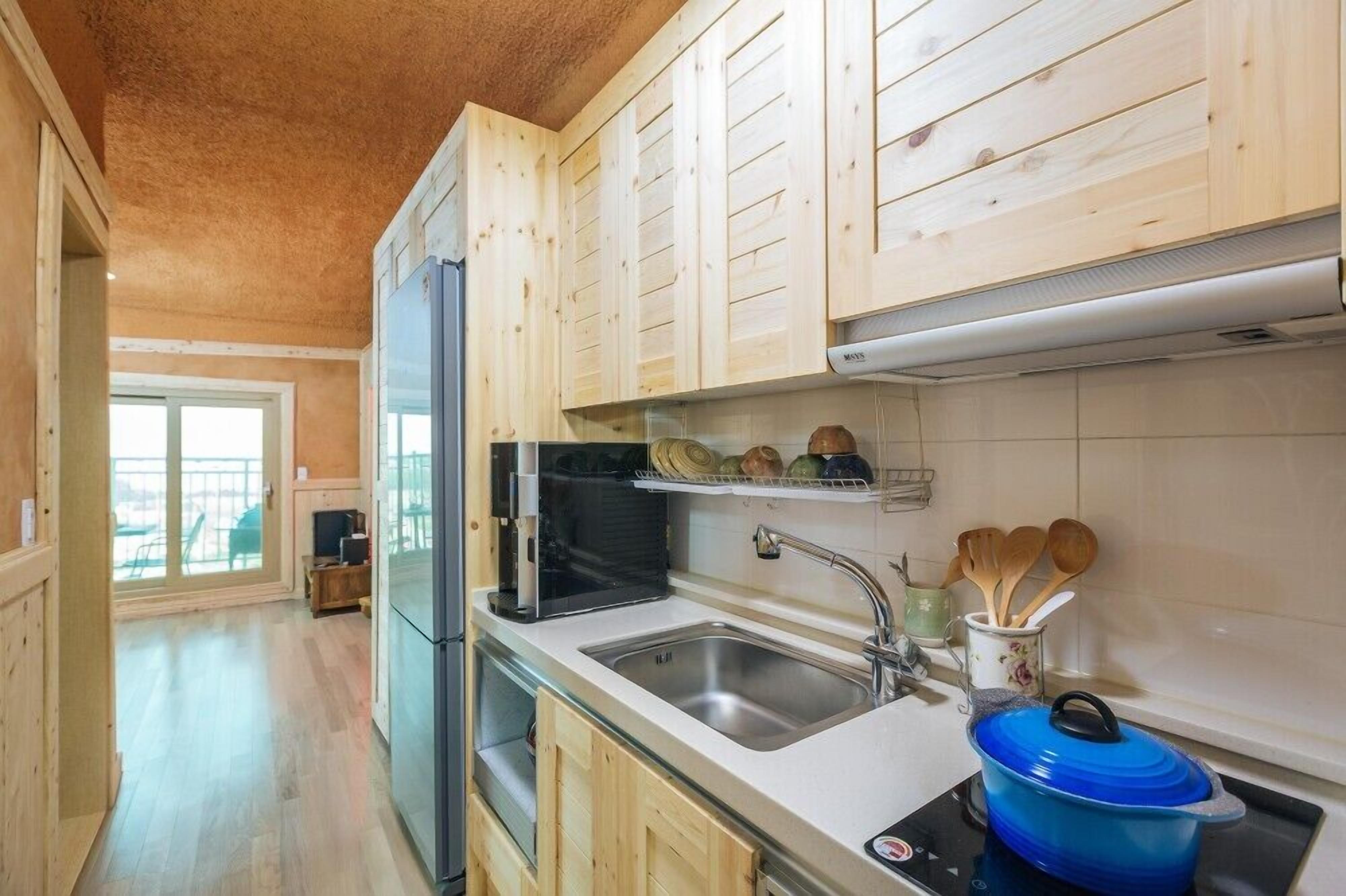 A kitchen with wooden cabinets, a stainless steel sink, and a blue pot on the stove.