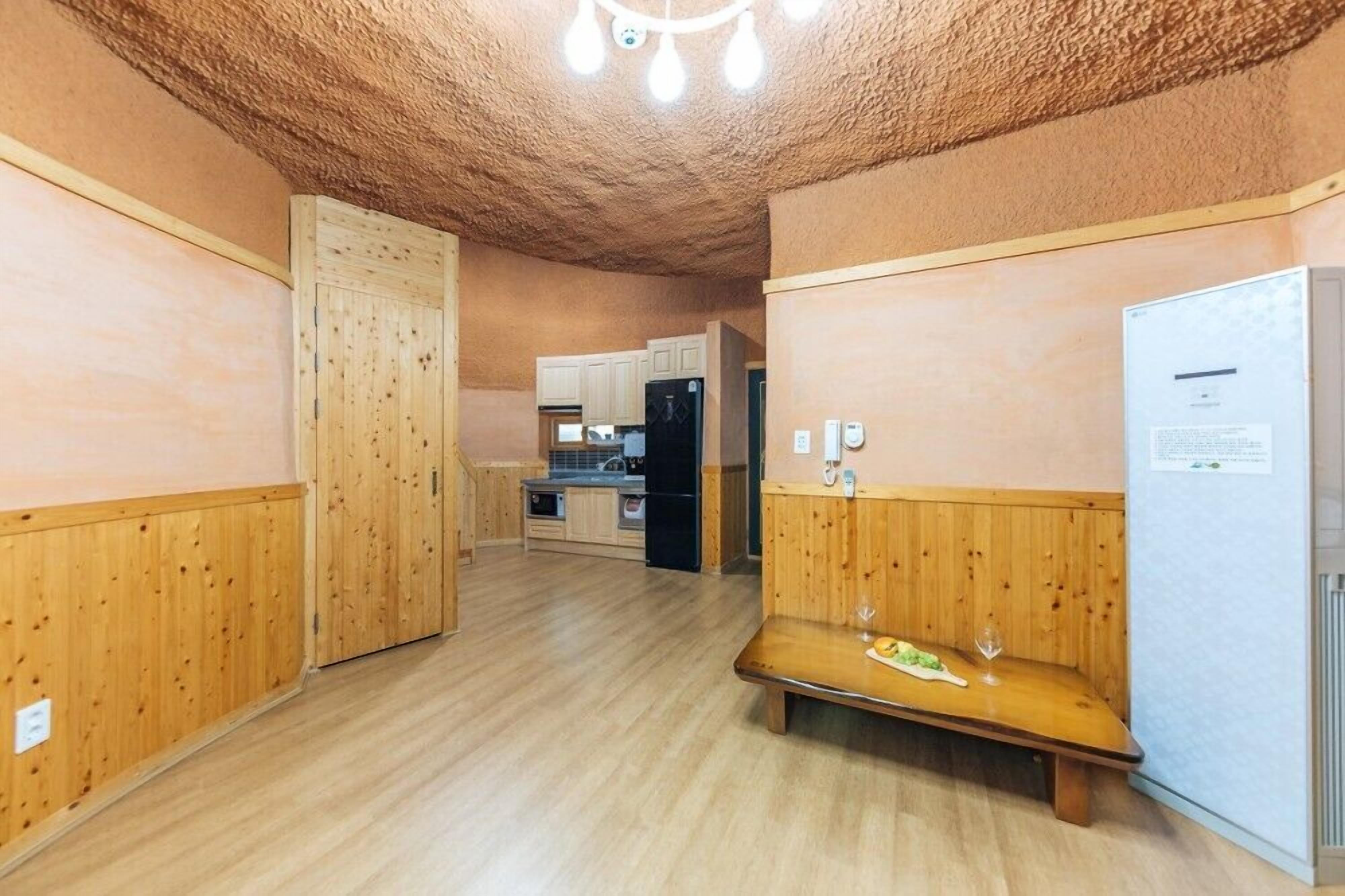 A compact kitchen with wooden cabinets, a bench, and a refrigerator.