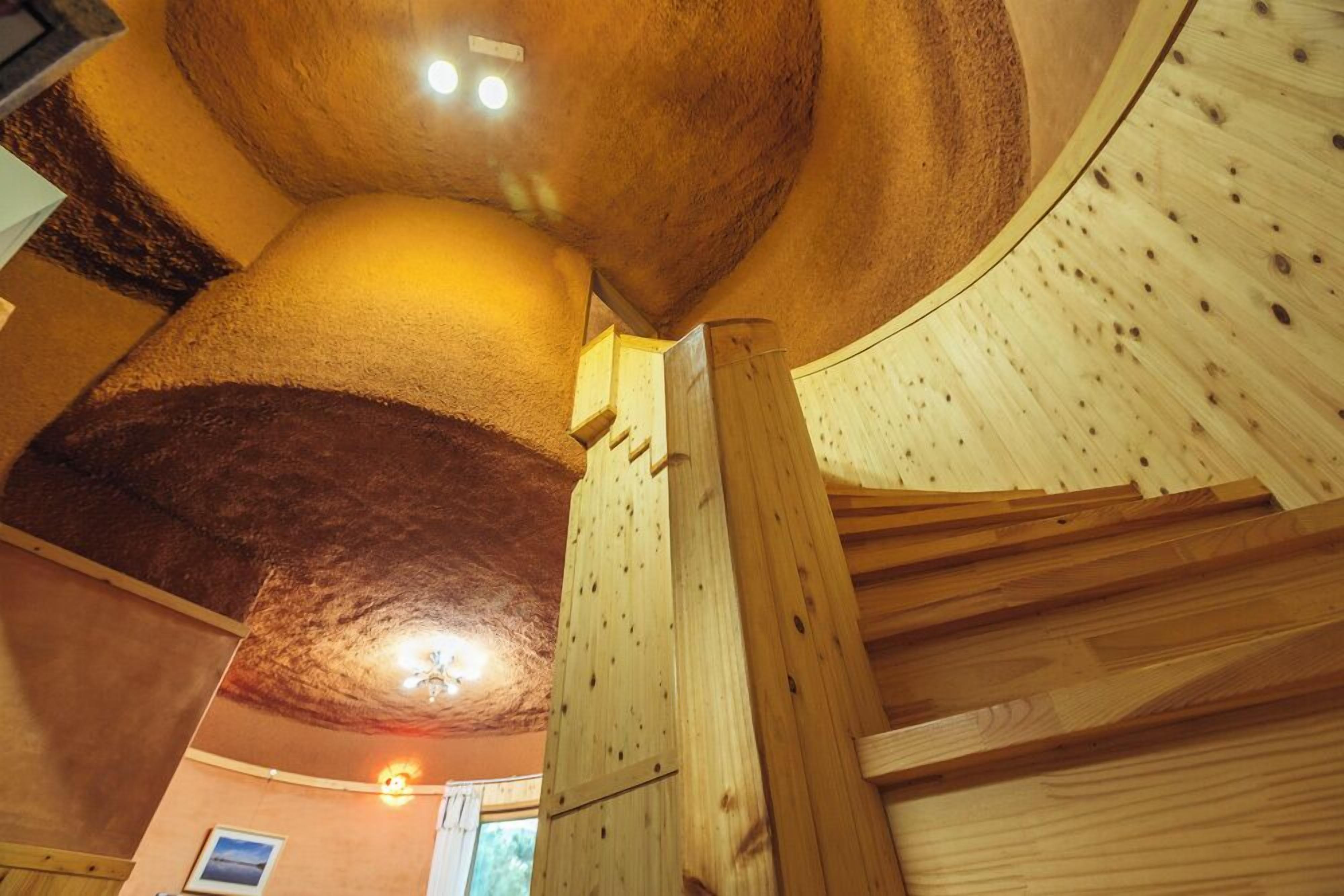 Een houten interieur met een gebogen plafond, houten balken en een lamp.