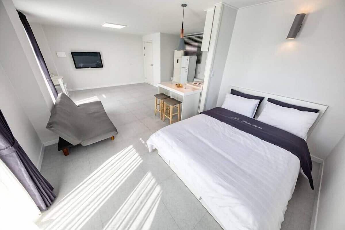 A modern hotel room with a bed, a desk, and a chair.