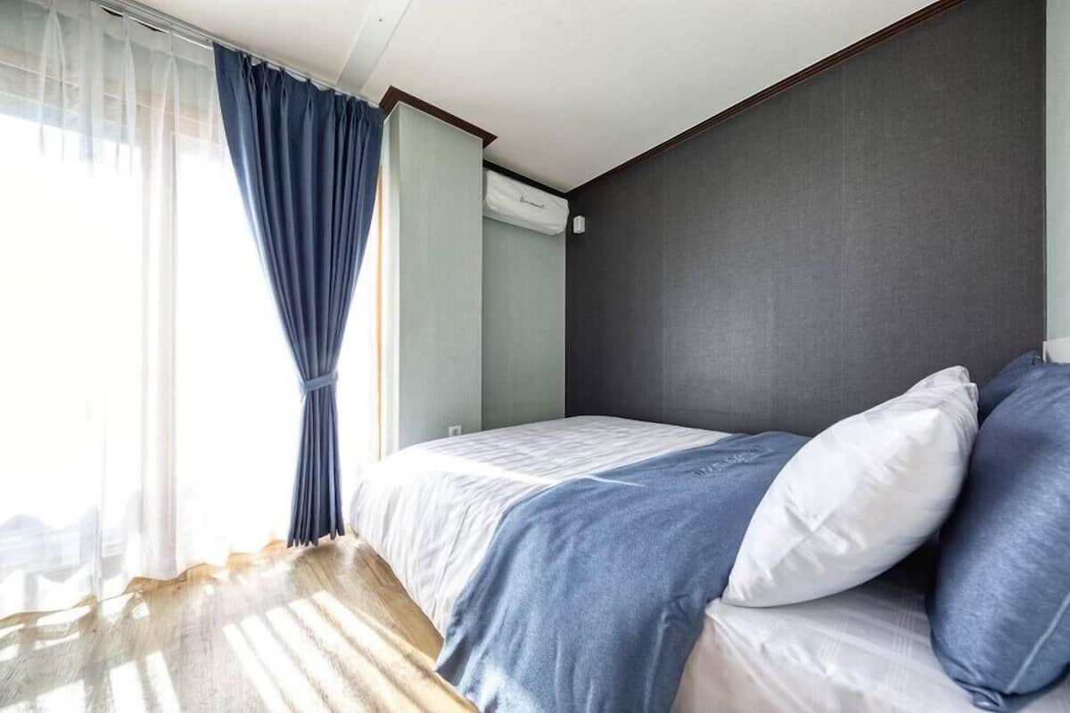 A hotel room with a bed, curtains, and a window.
