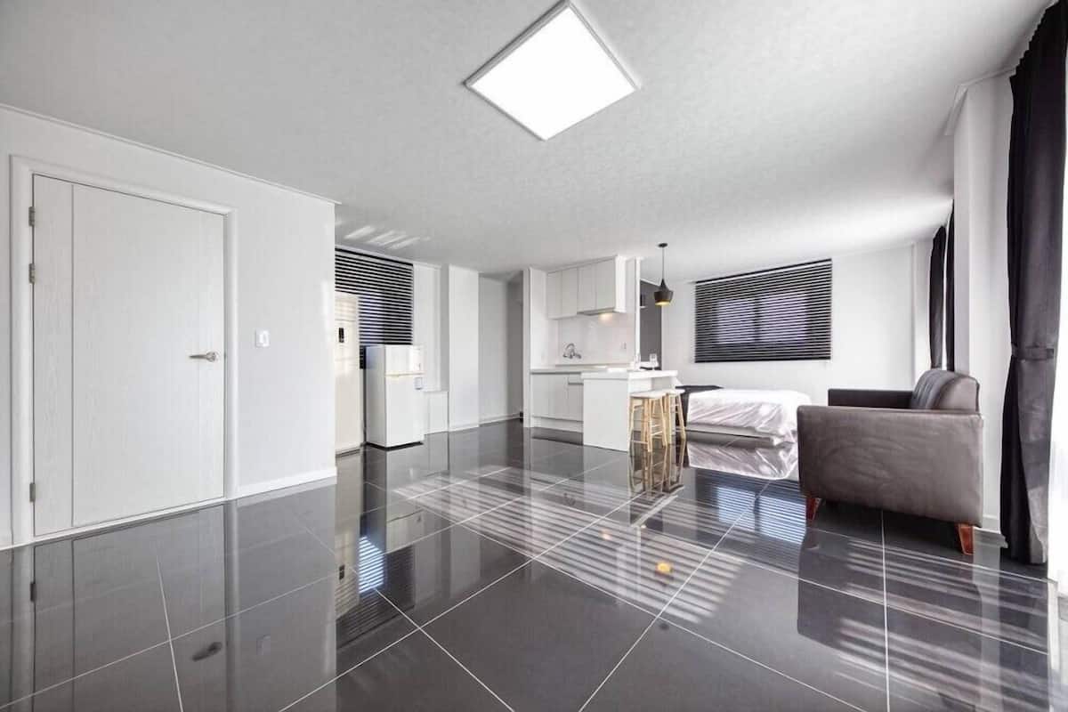 A modern apartment with a kitchen, dining area, and a living room with a sofa and a chair.