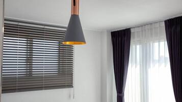 Ein Zimmer mit einer Deckenleuchte, einem Fenster mit Jalousien und einem Vorhang.