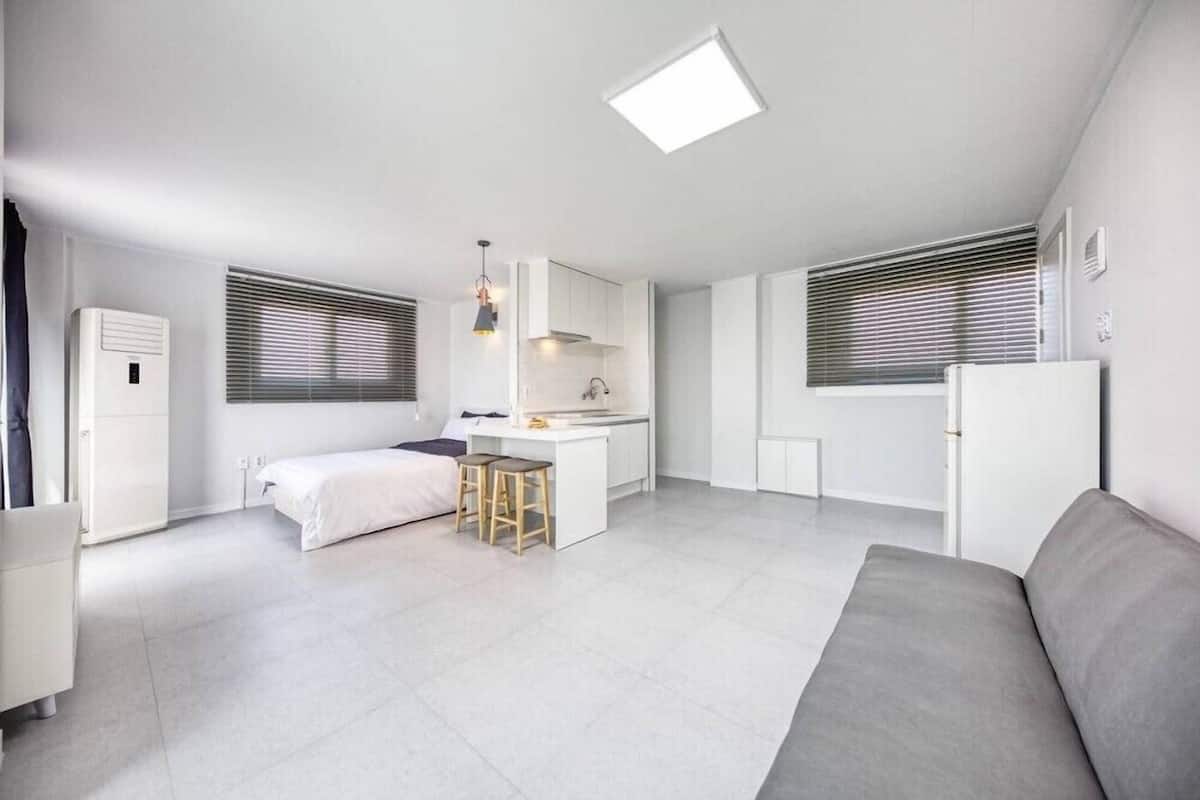 A compact, modern apartment with a kitchenette, a small dining area, and a sofa.