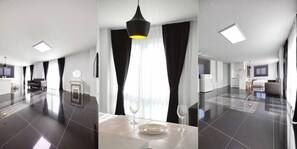 Une chambre d’hôtel moderne dotée d’un grand espace repas, d’un luminaire suspendu noir et offrant une vue sur la ville.