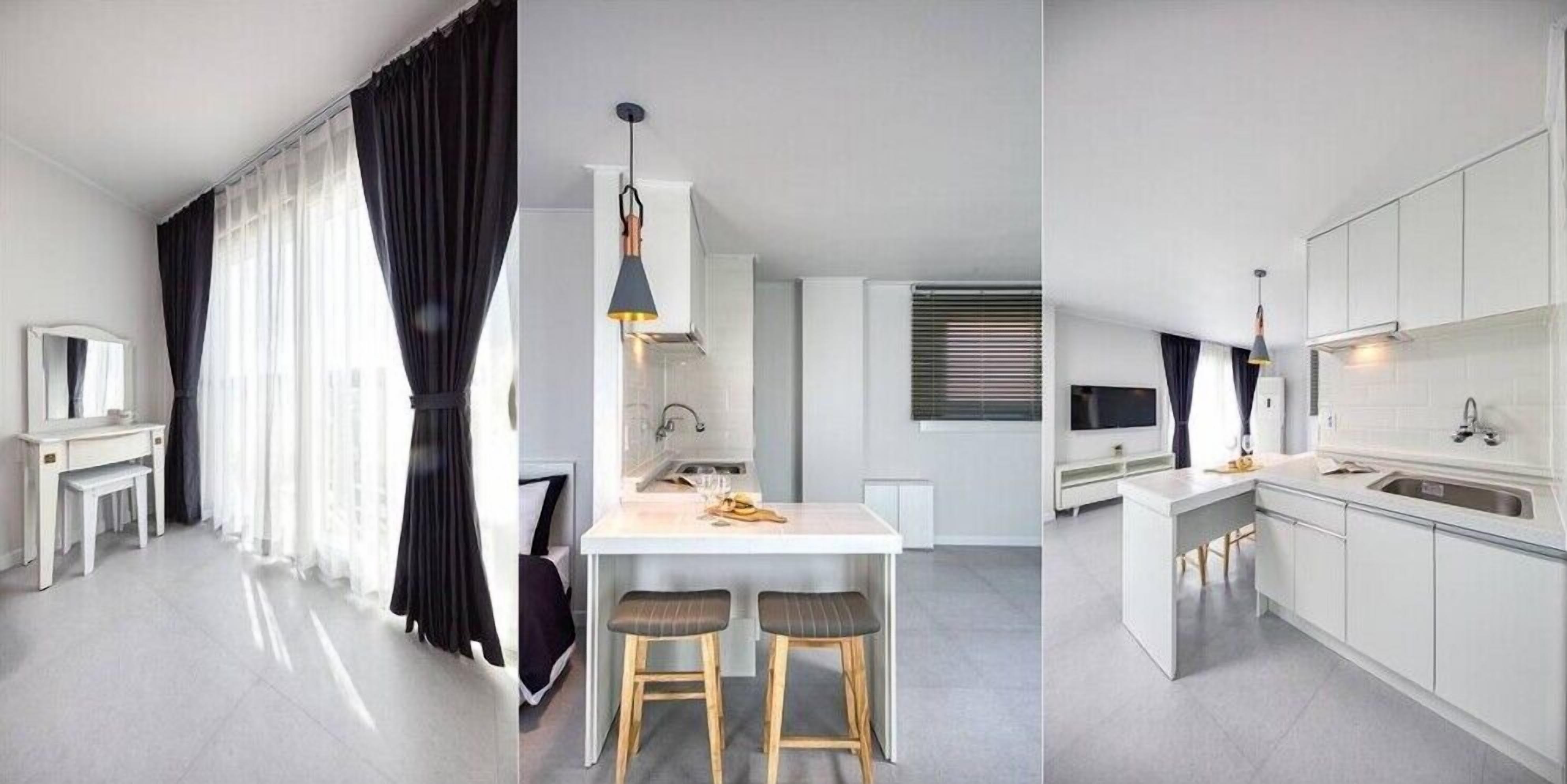 Een moderne keuken met witte kasten, een centraal eiland met krukken, en een hanglamp.