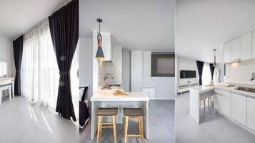 Een moderne keuken met witte kasten, een centraal eiland met krukken, en een hanglamp.